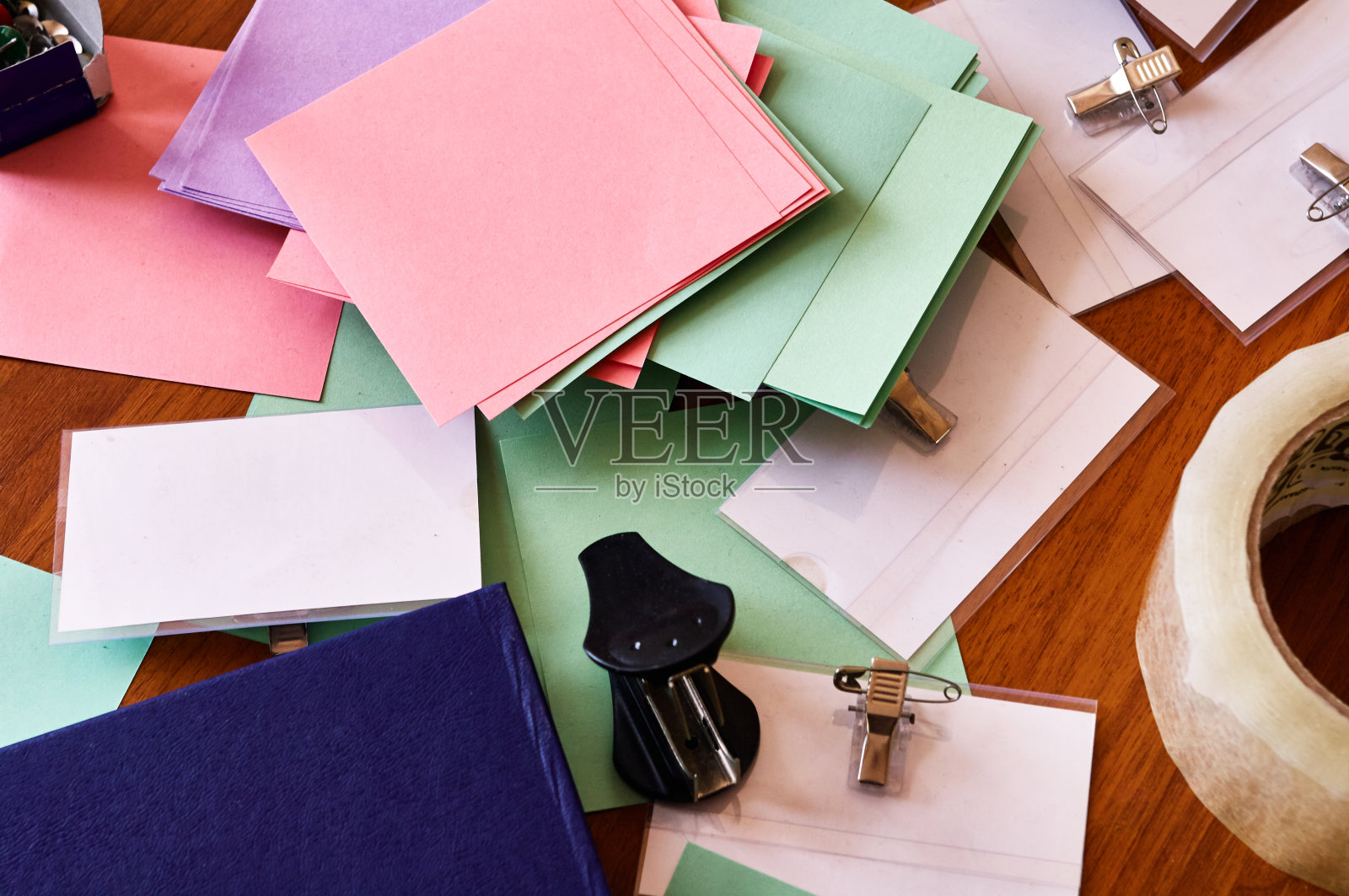 桌子上杂乱的办公用品，五颜六色的贴纸，订书机，笔记本，胶带，纽扣，徽章照片摄影图片