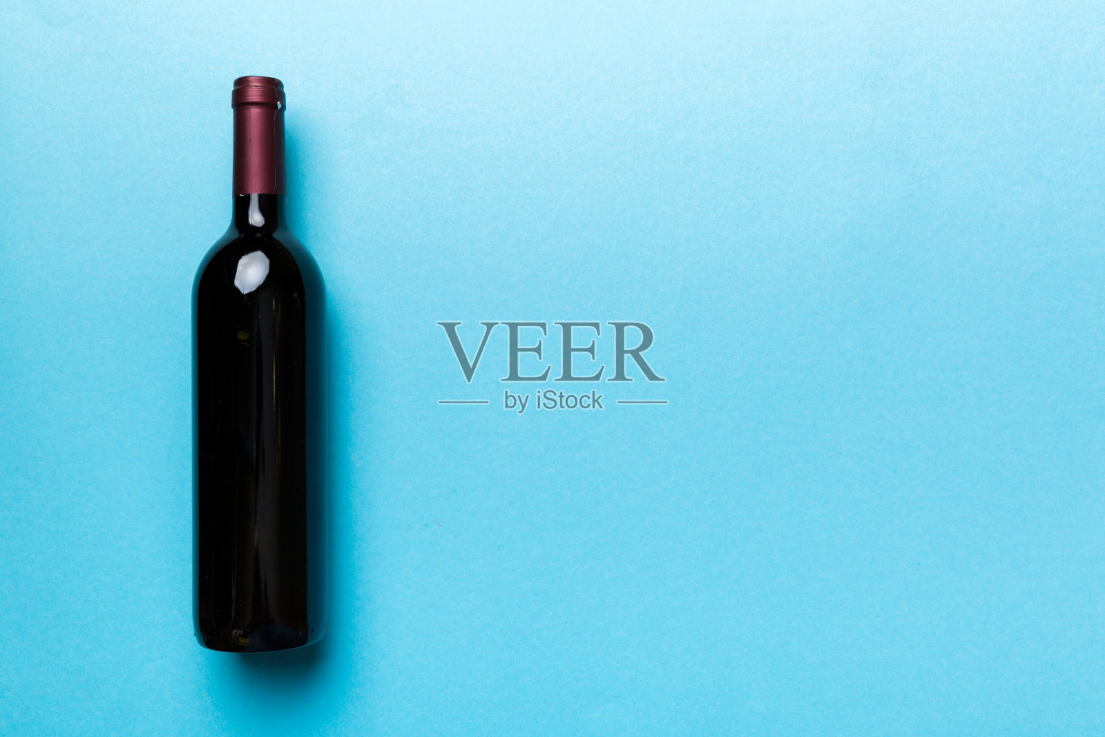 一瓶红酒在彩色的桌子上。平躺，顶视图与复制空间照片摄影图片