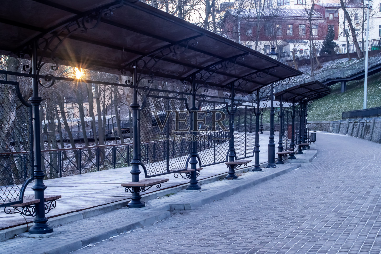 清晨冬日公园的小巷。有锻铁长椅和灯笼的小巷。美丽的早晨。空城的概念。乌克兰基辅市中心的现代金属长椅照片摄影图片