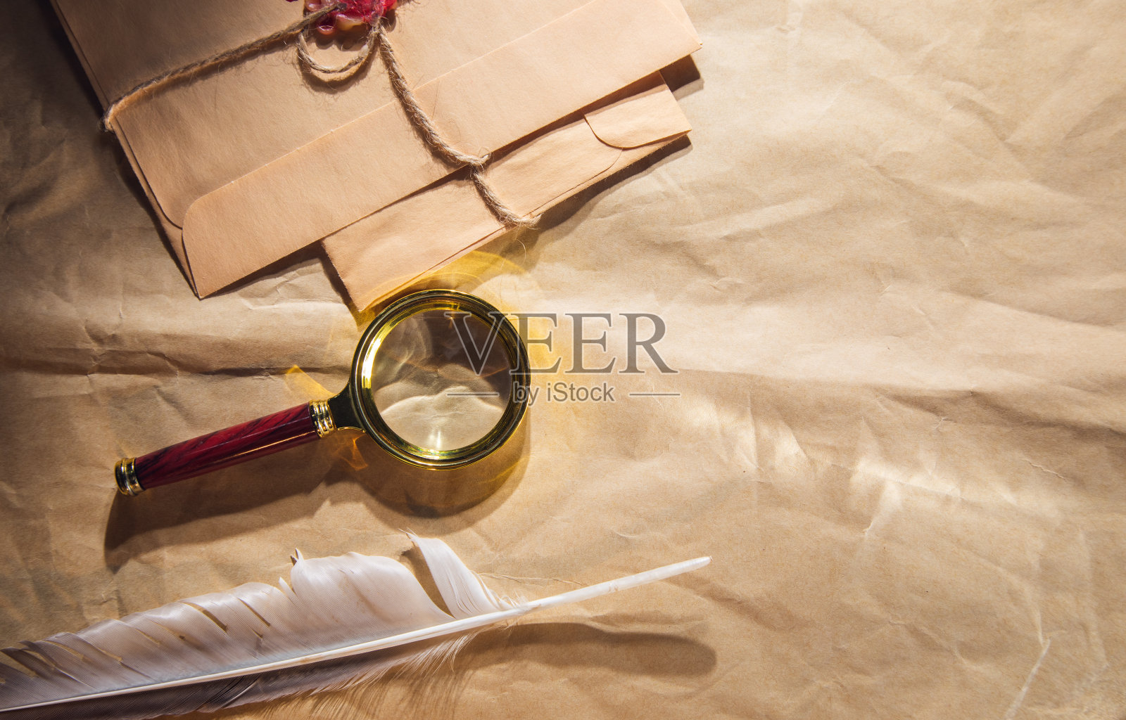 羽毛，字母和放大镜在旧纸上照片摄影图片