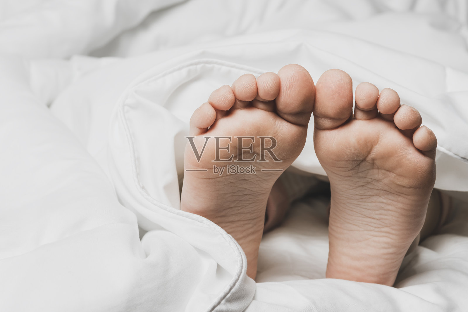 孩子的腿上盖着白色的床单。家的温暖和舒适。照片摄影图片