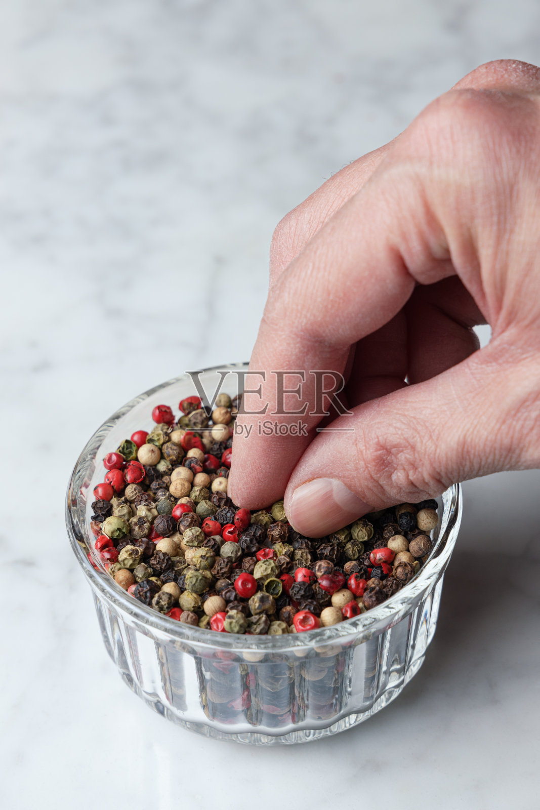 用手从碗里抓辣椒籽照片摄影图片