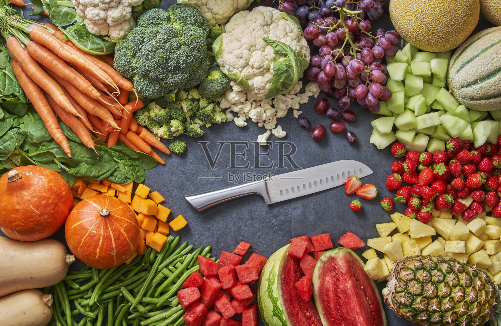 有很多水果和蔬菜，中间有一把刀照片摄影图片