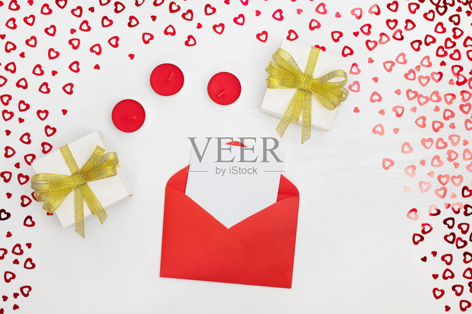 手工纸组成礼品盒、蜡烛、信封、传单。白色木桌上亮片心形图案。内容为生日，情人节，妇女节。平躺，顶视图，关闭，复制空间照片摄影图片