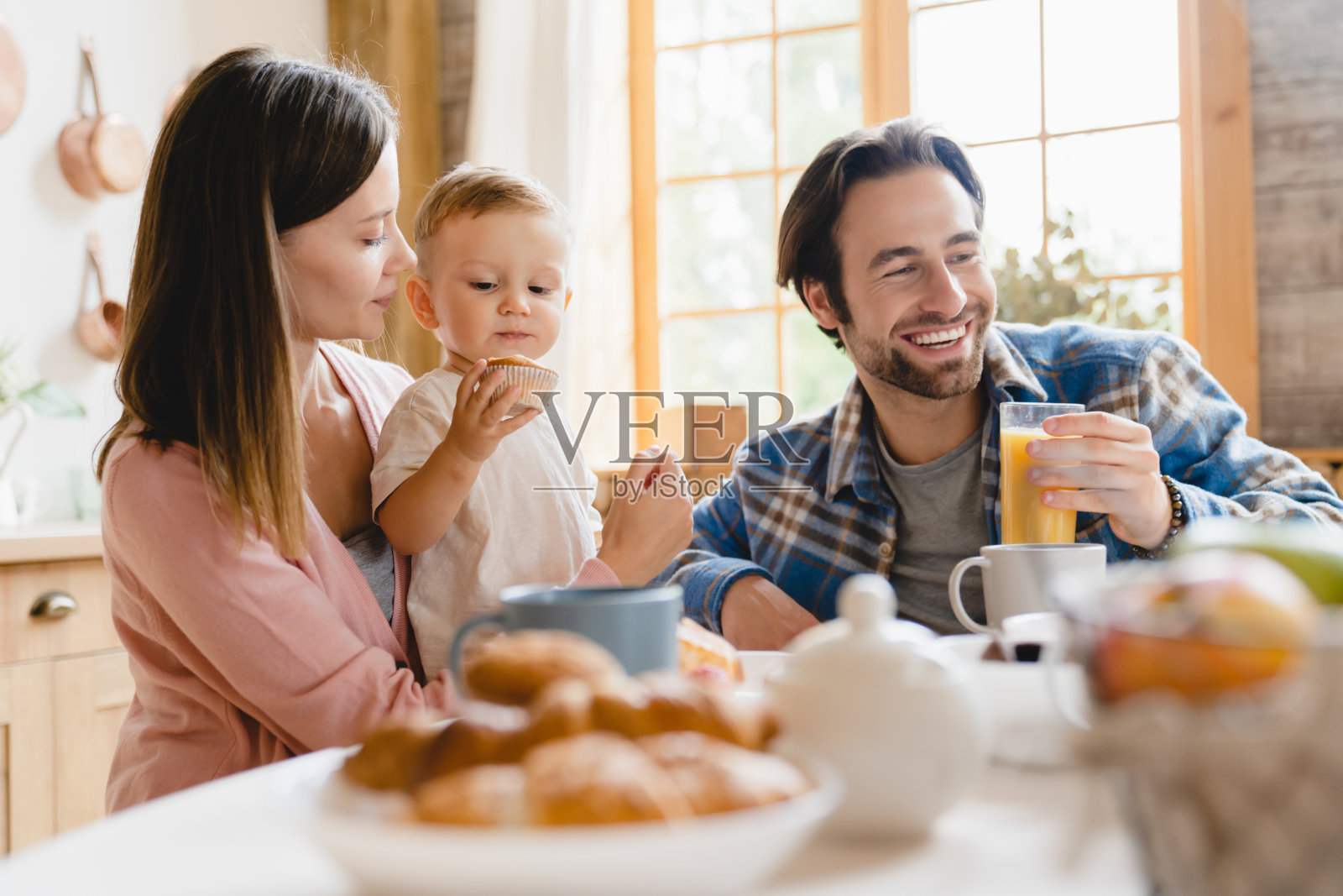 幸福的家庭的时刻。白种人年轻的父母正在吃早餐，带着小孩，小孩，蹒跚学步的儿子，女儿，婴儿，婴儿在家里厨房里。生育和收养照片摄影图片
