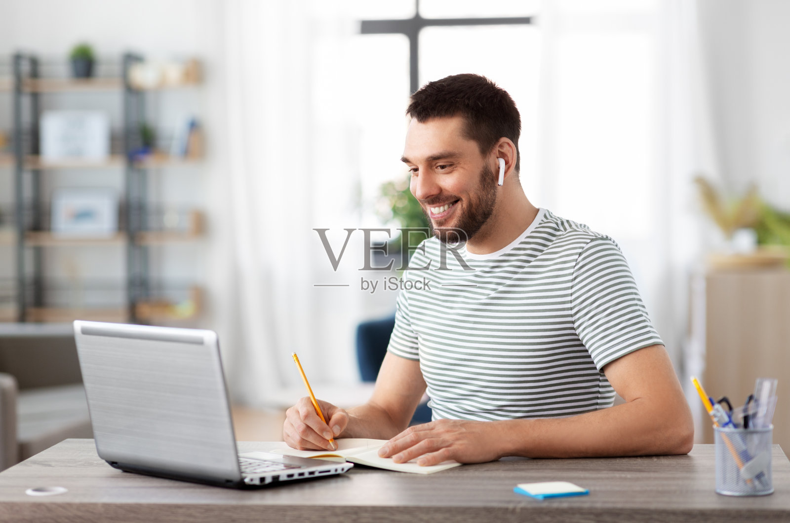 一个在家带着笔记本，耳机和笔记本电脑的男人照片摄影图片