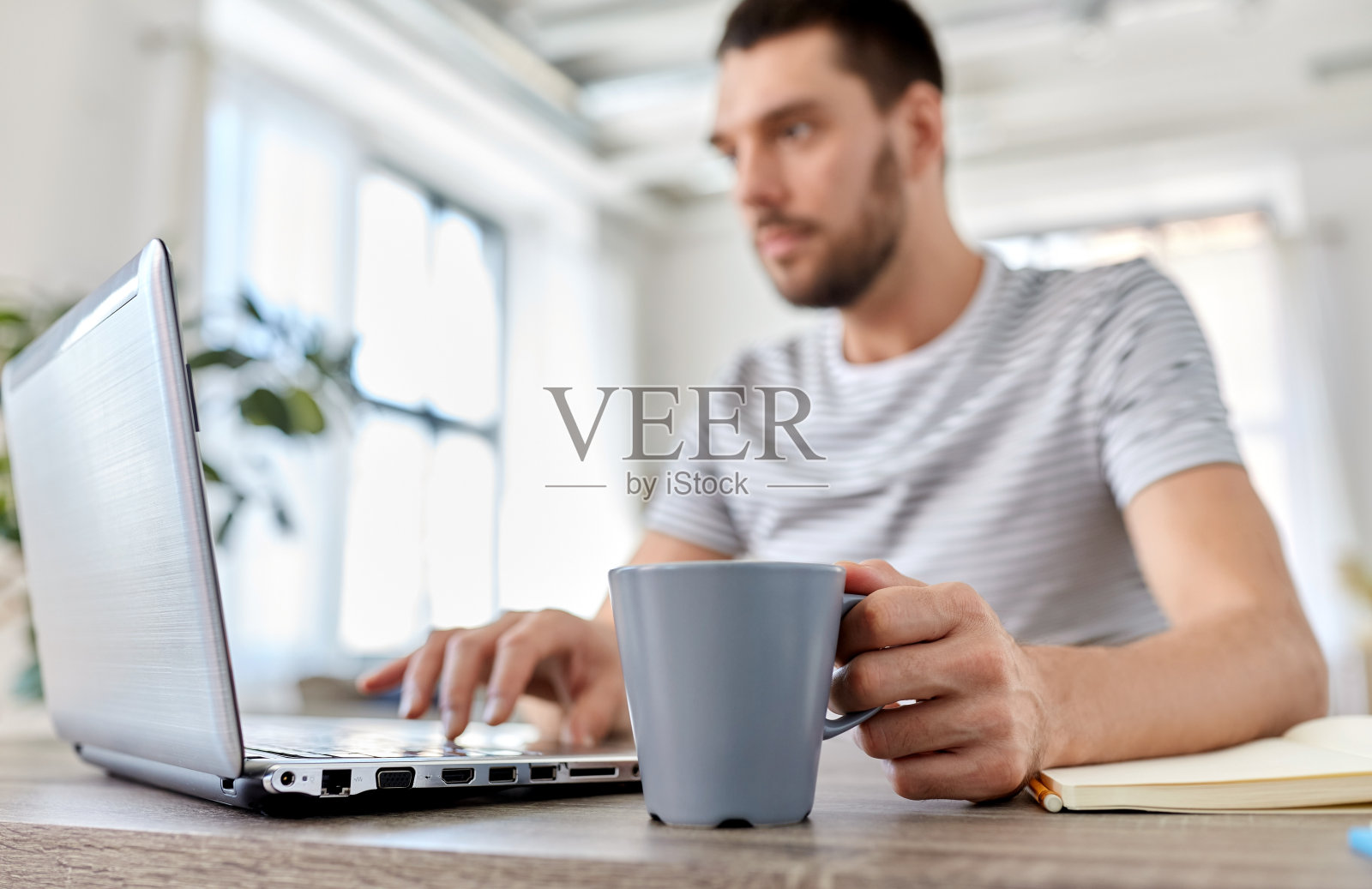 男人拿着笔记本电脑在家里办公室喝咖啡照片摄影图片
