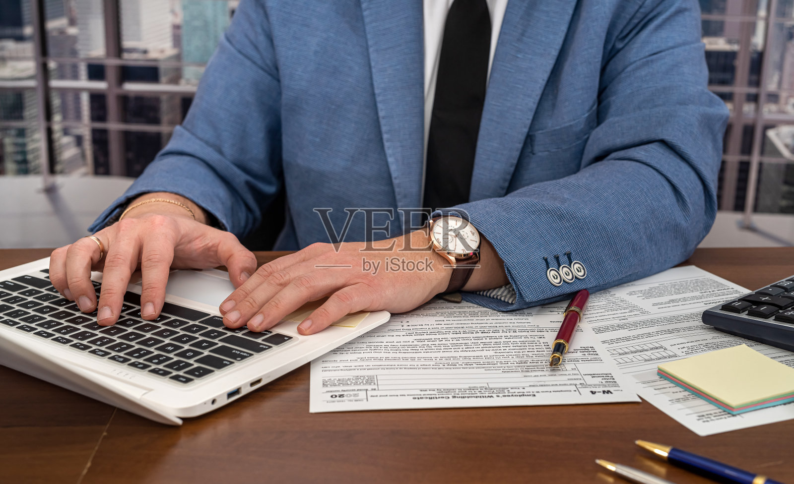 英俊的男性商人正坐在桌边填写美国税务表格1040。照片摄影图片