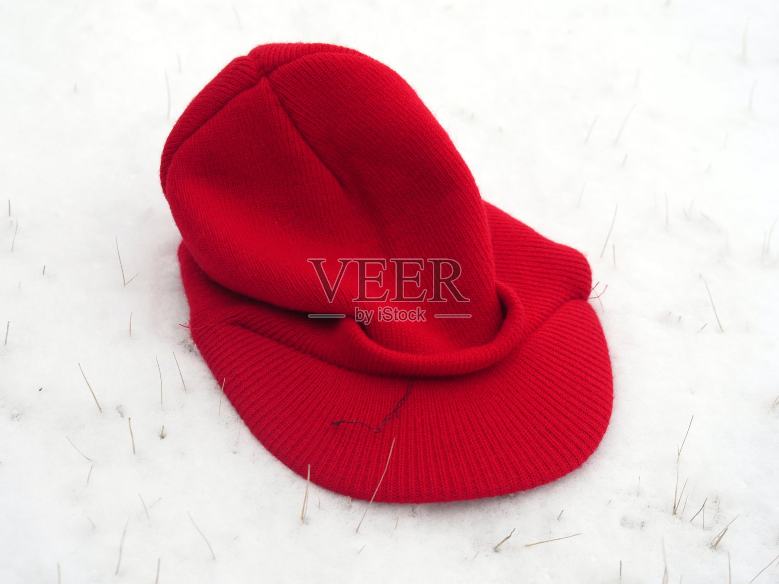 白雪覆盖的地面上一顶红帽子的特写照片摄影图片