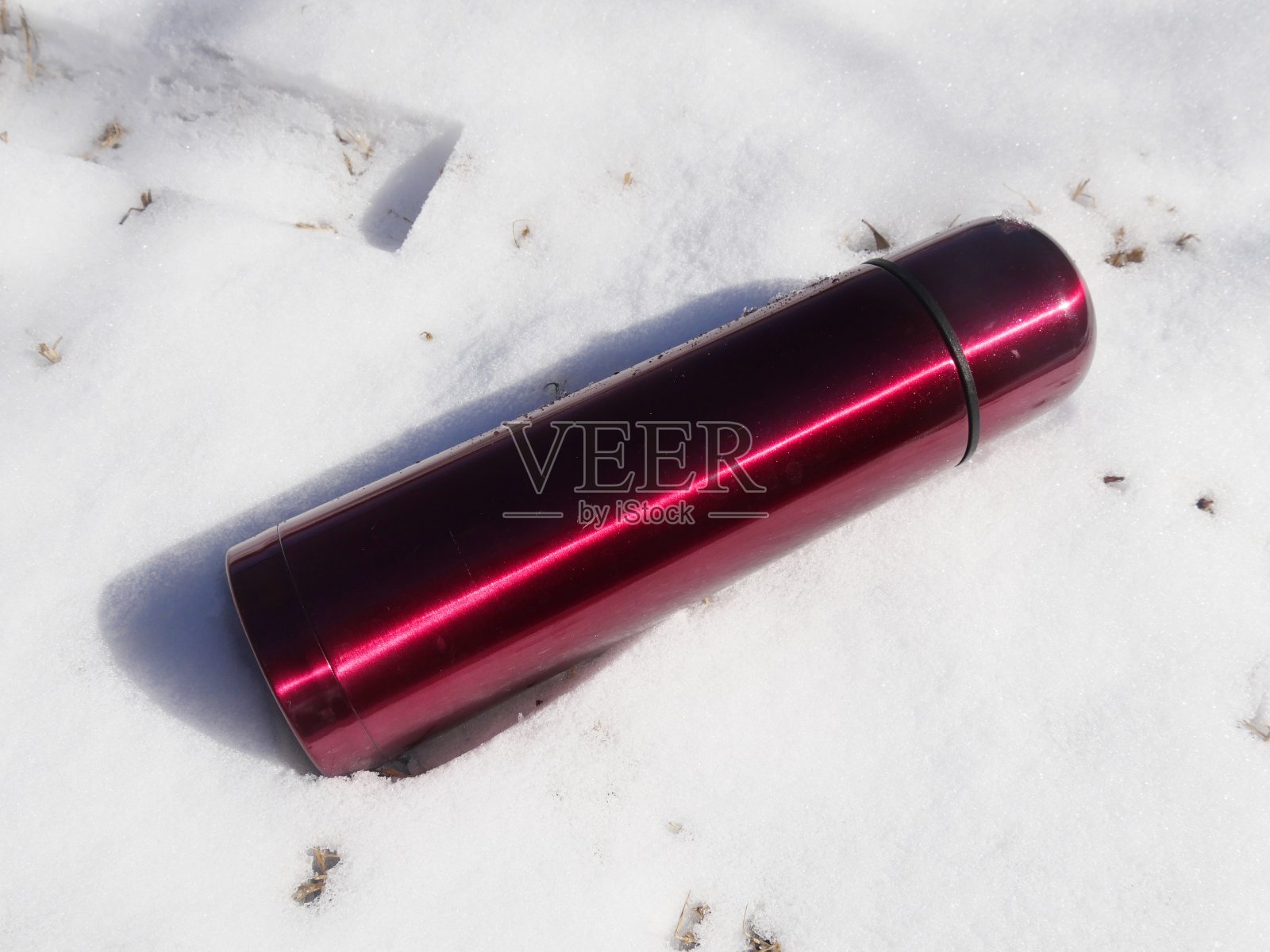 白雪覆盖的地面上的红色保温饮料容器照片摄影图片