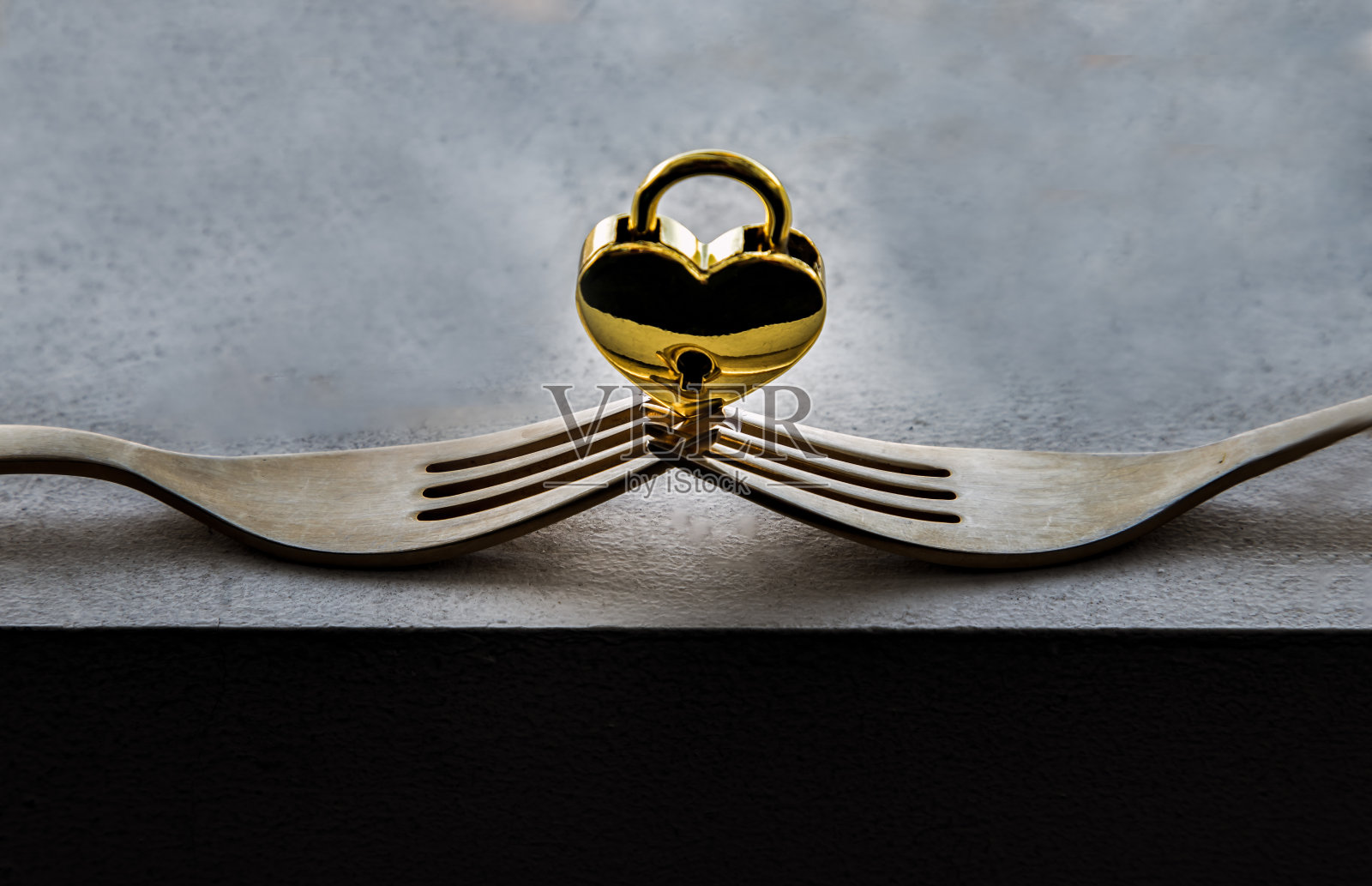 两个交织在一起的金叉构成了一个平衡的金色心形爱情挂锁。照片摄影图片