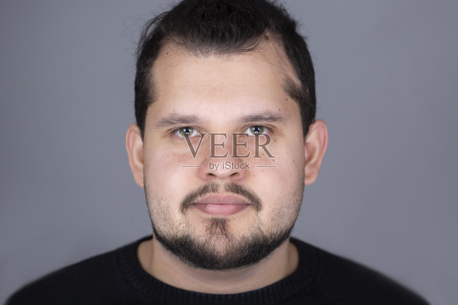 年轻拉丁男子工作室的大头照带着小小的微笑照片摄影图片