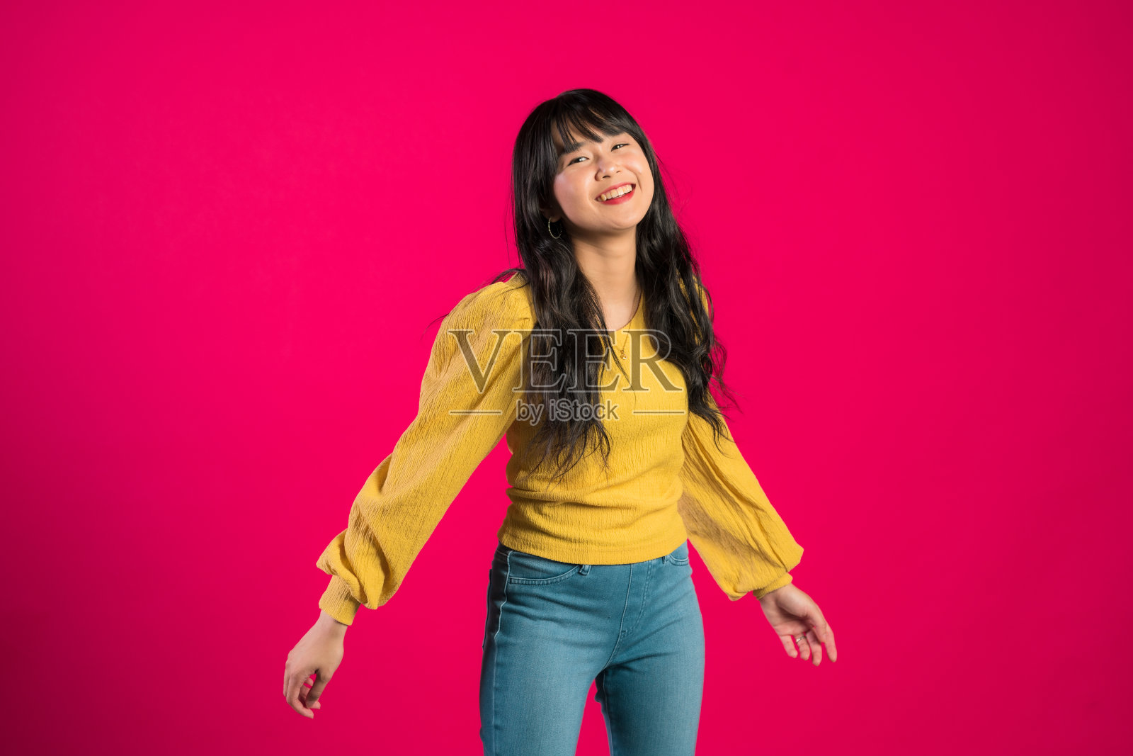 幸福的女人张开的手在前面的粉红色。照片摄影图片