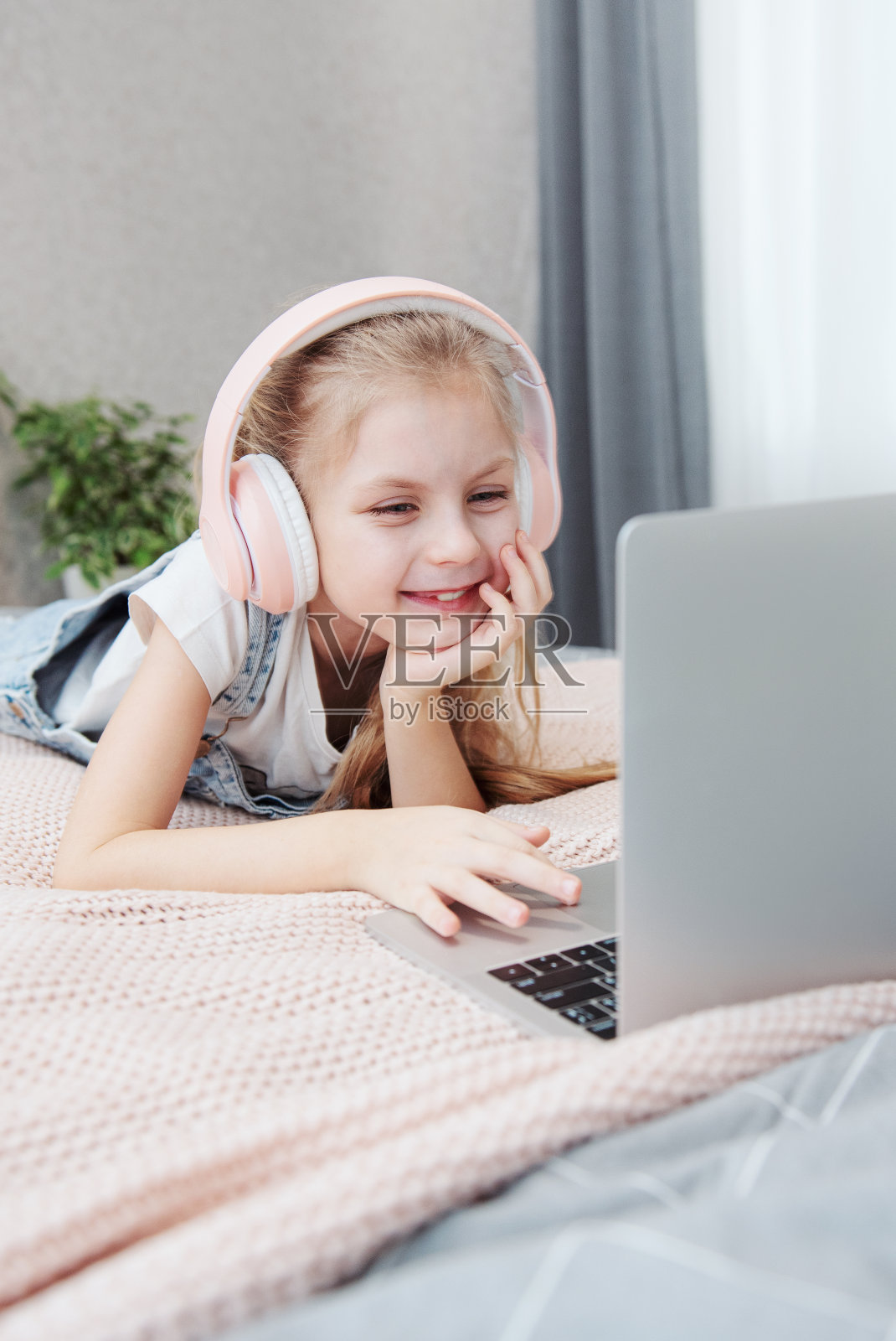 小女孩在卧室用笔记本电脑在线学习。照片摄影图片