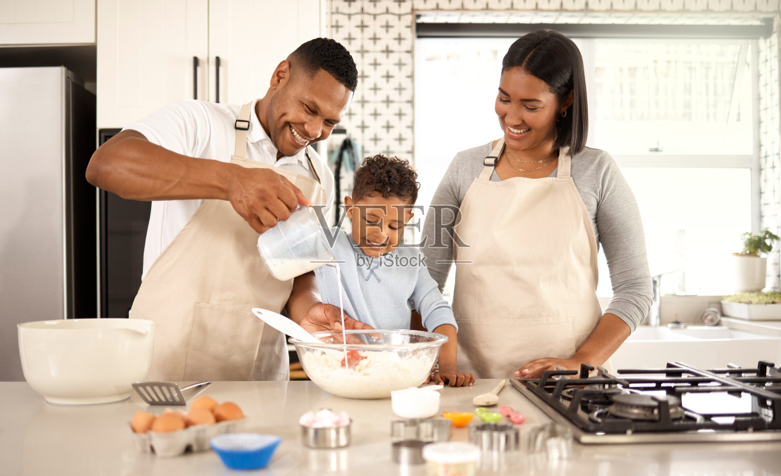 一个可爱的小男孩和他的父母在家里烤面包照片摄影图片