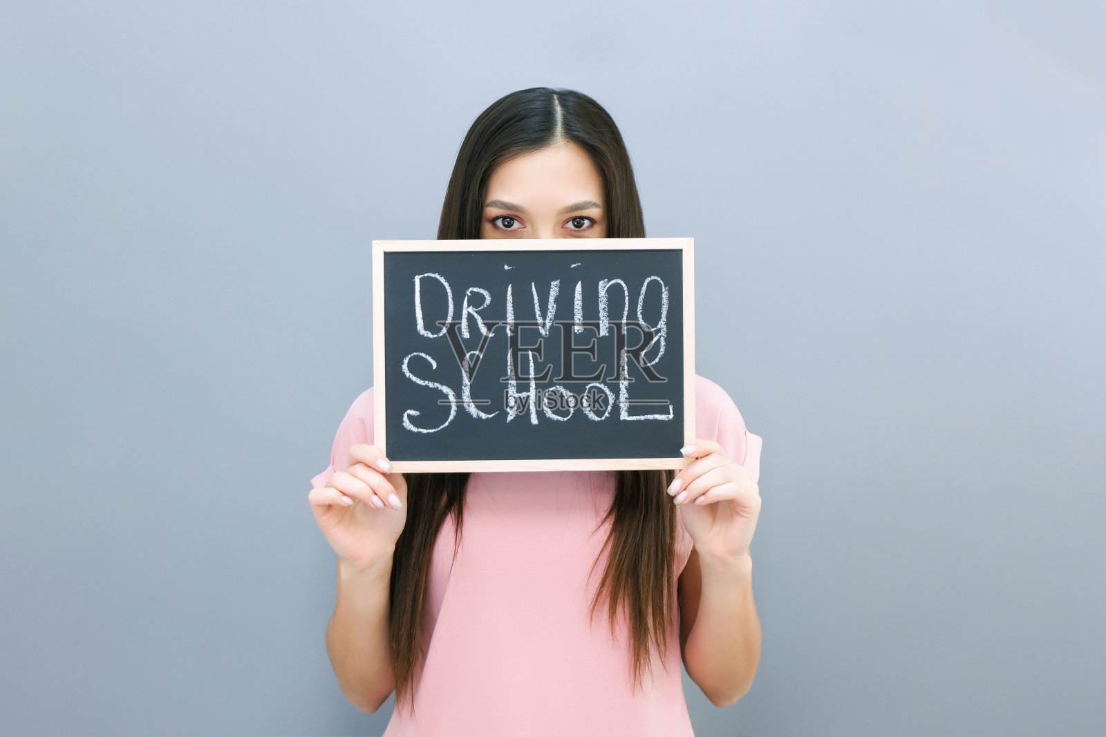 驾校的理念和理念，学生驾校考试通过，驾照通过，人像一个美丽快乐的年轻女子。在一个灰色孤立的背景照片摄影图片