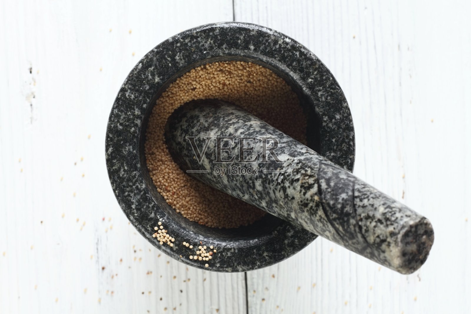 白色木桌上的石臼里放着苋菜籽。照片摄影图片