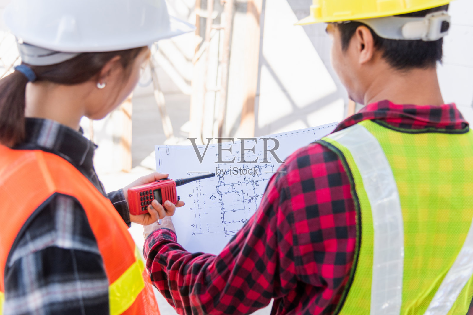 建筑师和业主在施工现场讨论建筑平面图照片摄影图片