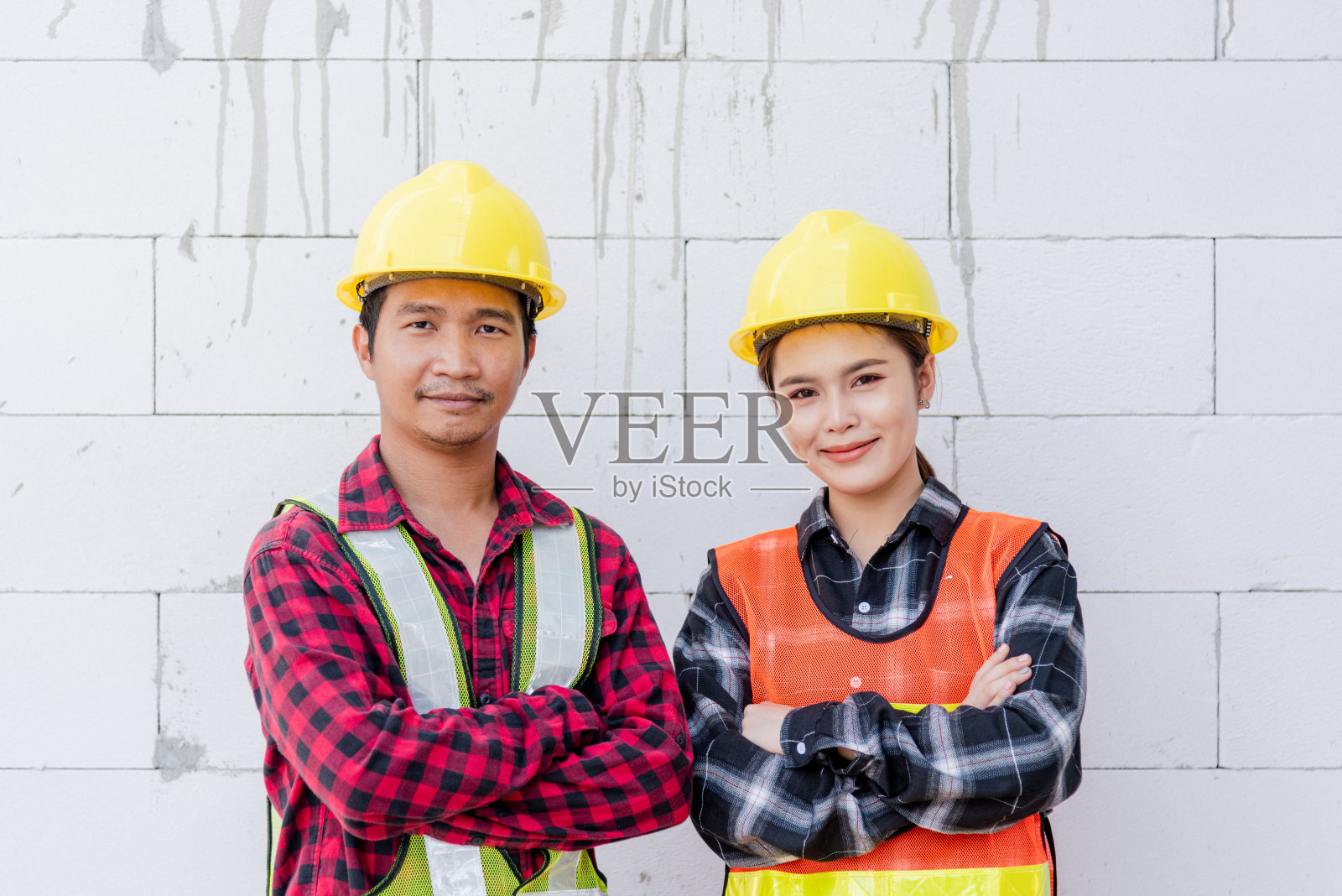 女建筑师和男建筑师的肖像，头戴安全帽，身穿背心，站在建筑施工现场照片摄影图片