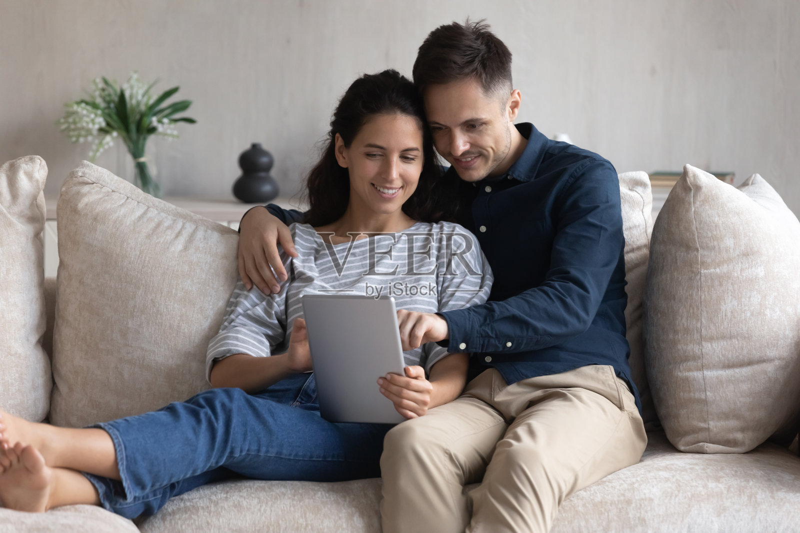 微笑的年轻夫妇坐在沙发上一起使用平板电脑照片摄影图片
