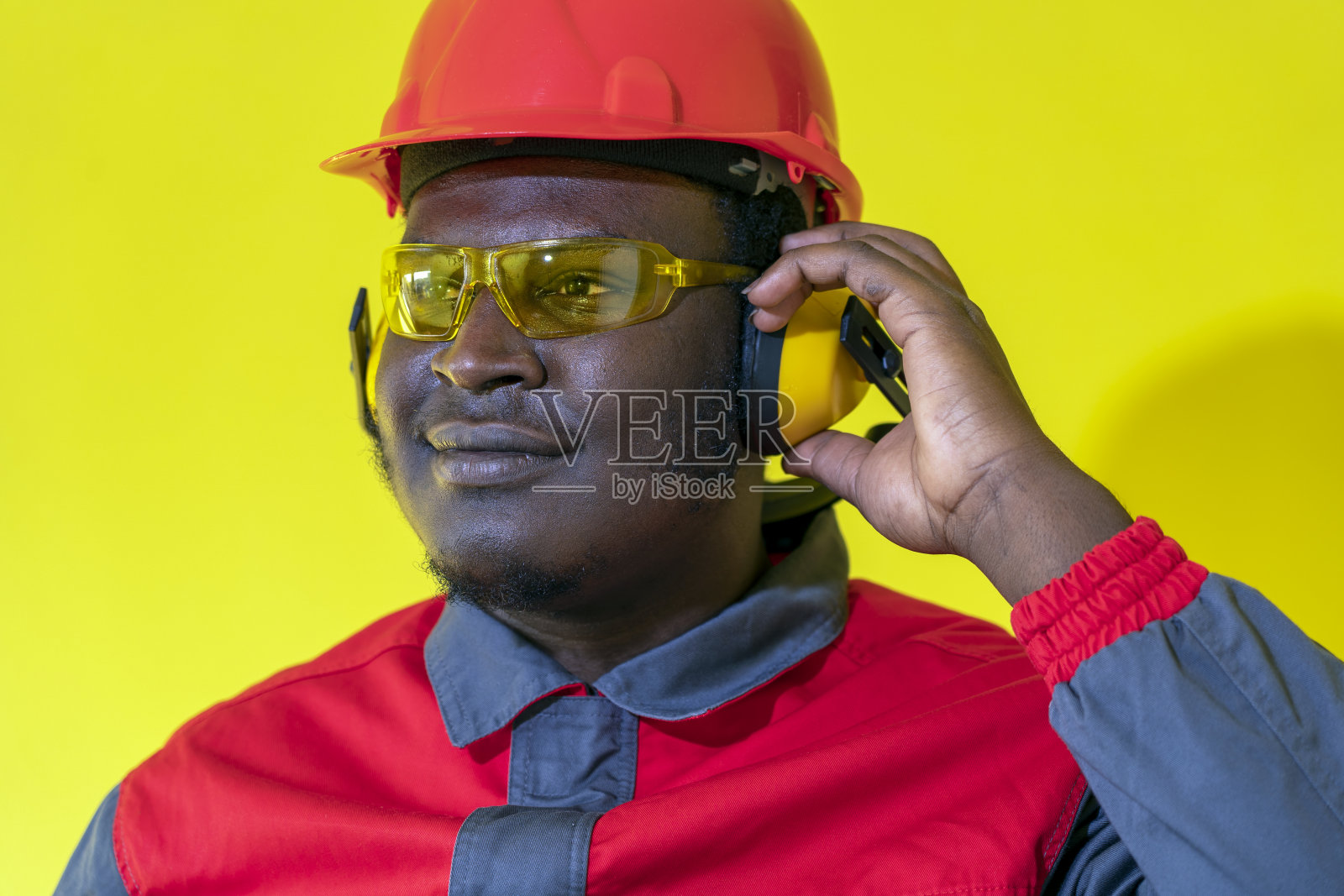 年轻的非裔美国工人在个人防护装备中对抗黄色背景照片摄影图片