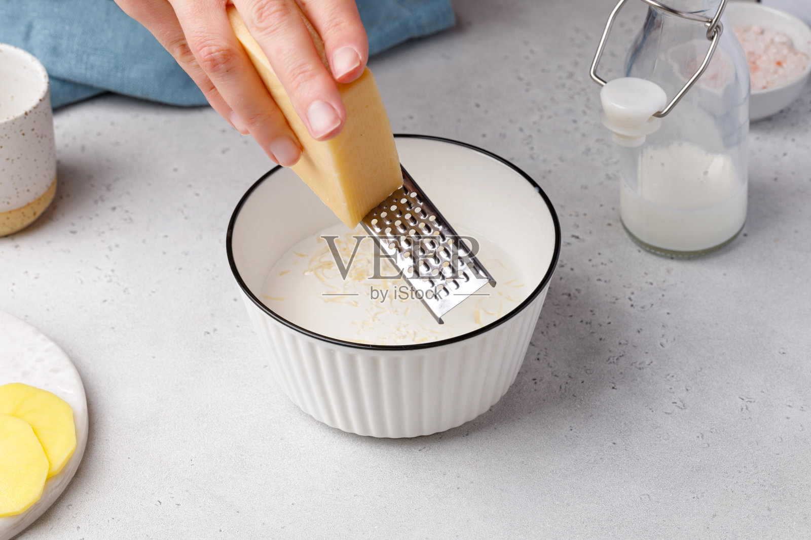 一步一步的烤土豆食谱。用手把奶酪擦到碗里做酱汁照片摄影图片