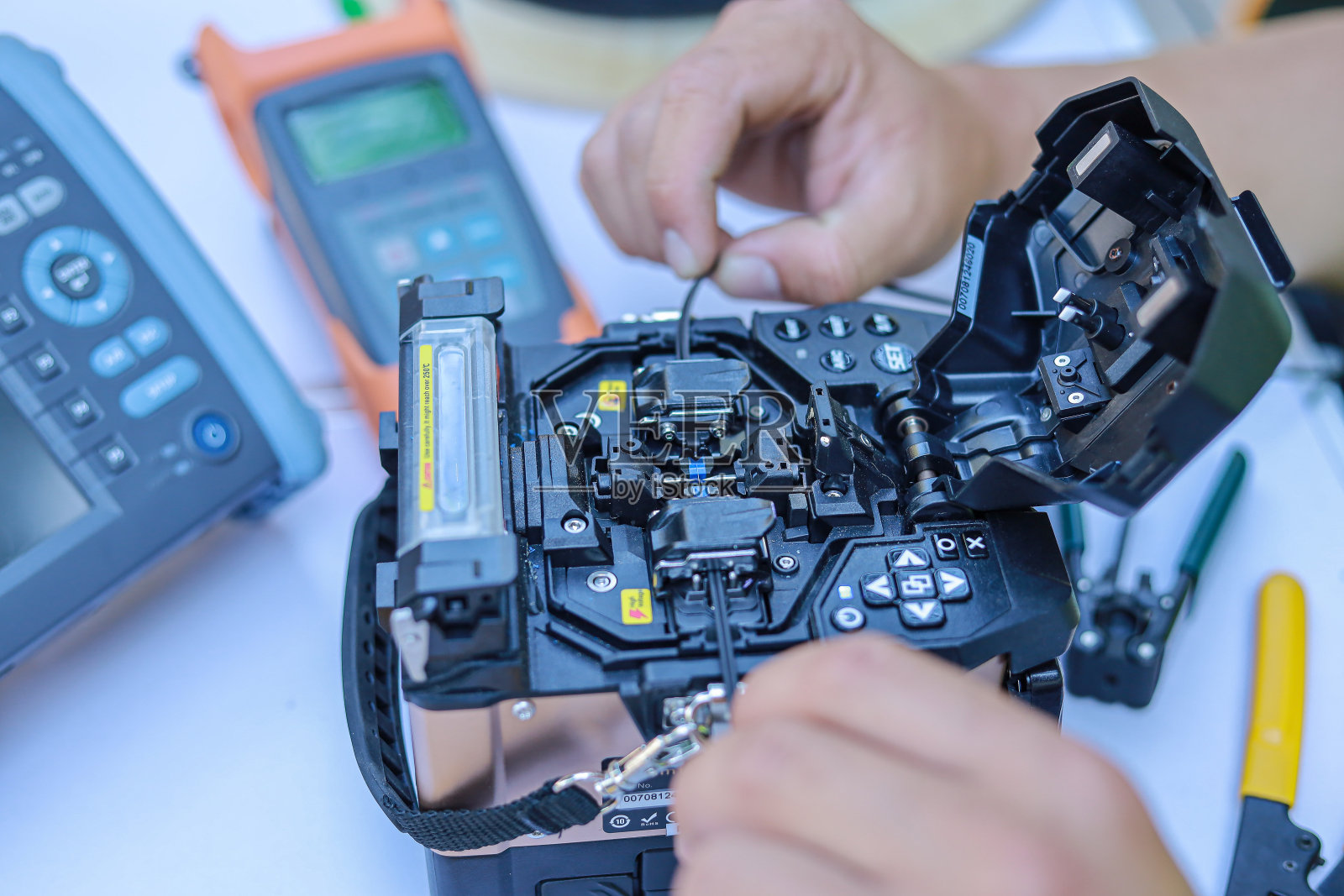 使用光纤熔接机连接互联网信号和电线，光纤熔接机在工作照片摄影图片