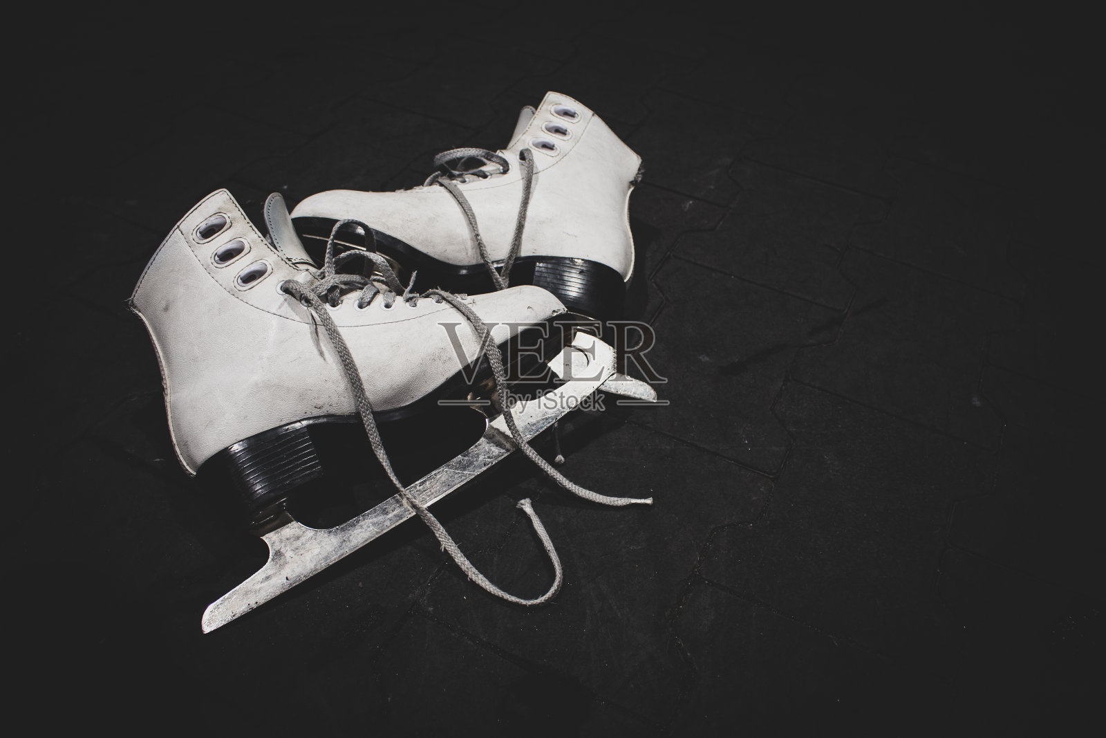 一双黑色背景的冰花溜冰鞋。冬季运动活动。白色溜冰鞋与刀刃，孤立。趣味爱好概念。积极的生活方式。照片摄影图片