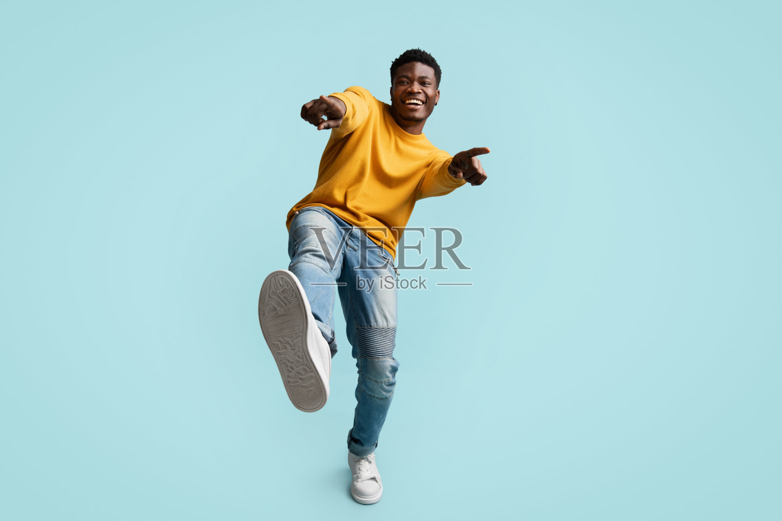 无忧无虑的英俊黑人在蓝色上摆姿势，笑着，打着手势照片摄影图片