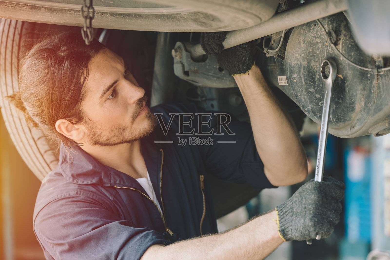 男机修工，汽车维修人员，在车库工作的工人，修理传动轴问题照片摄影图片