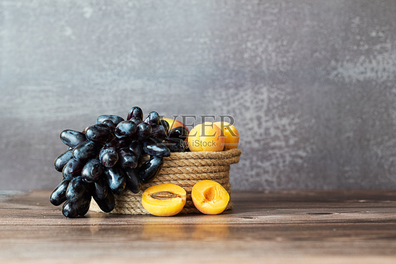 黄麻篮子里的葡萄和深色背景上的杏子照片摄影图片
