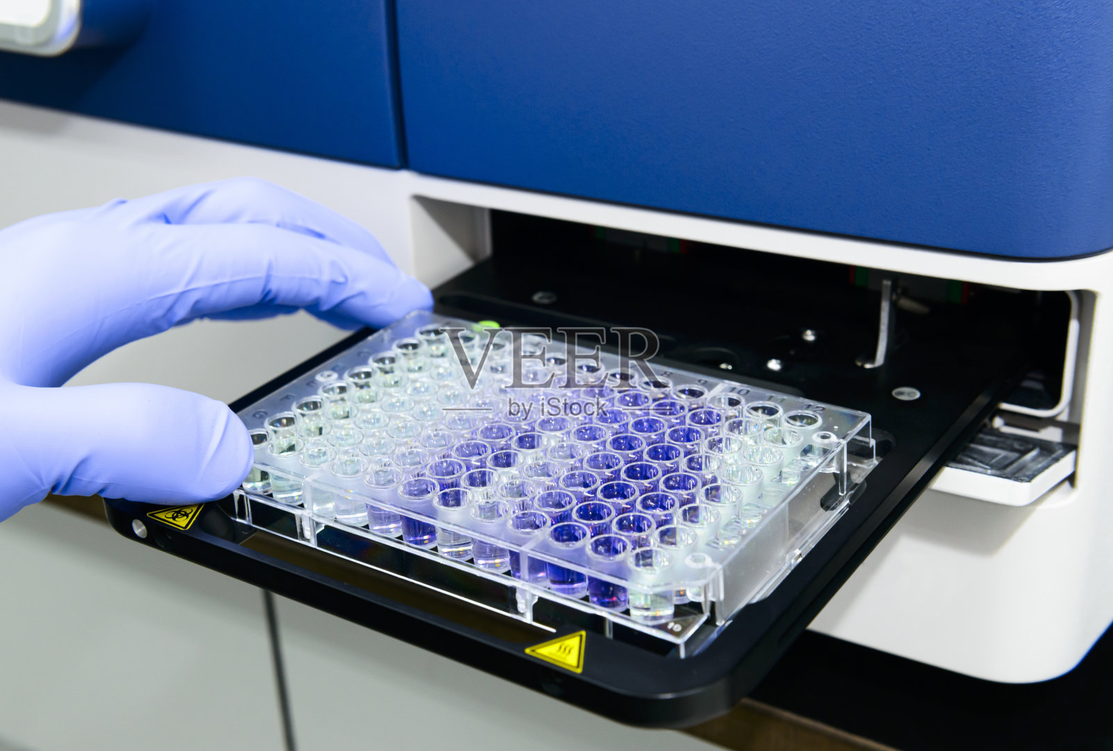科学家正在把96孔微板放入读板仪中照片摄影图片