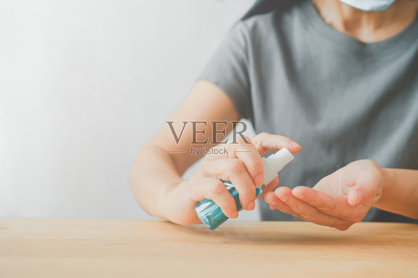 老年妇女向手上喷洒酒精，以提高保护冠状病毒的意识、人群、社会或群体免疫概念照片摄影图片