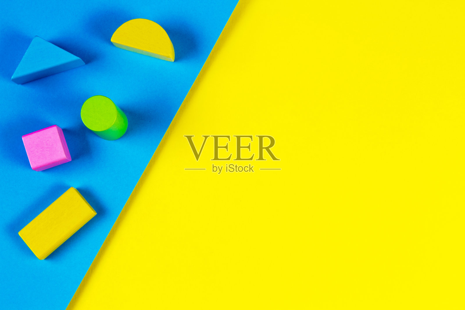 几何黄色和蓝色背景上的木制彩色块。俯视图，平躺照片摄影图片