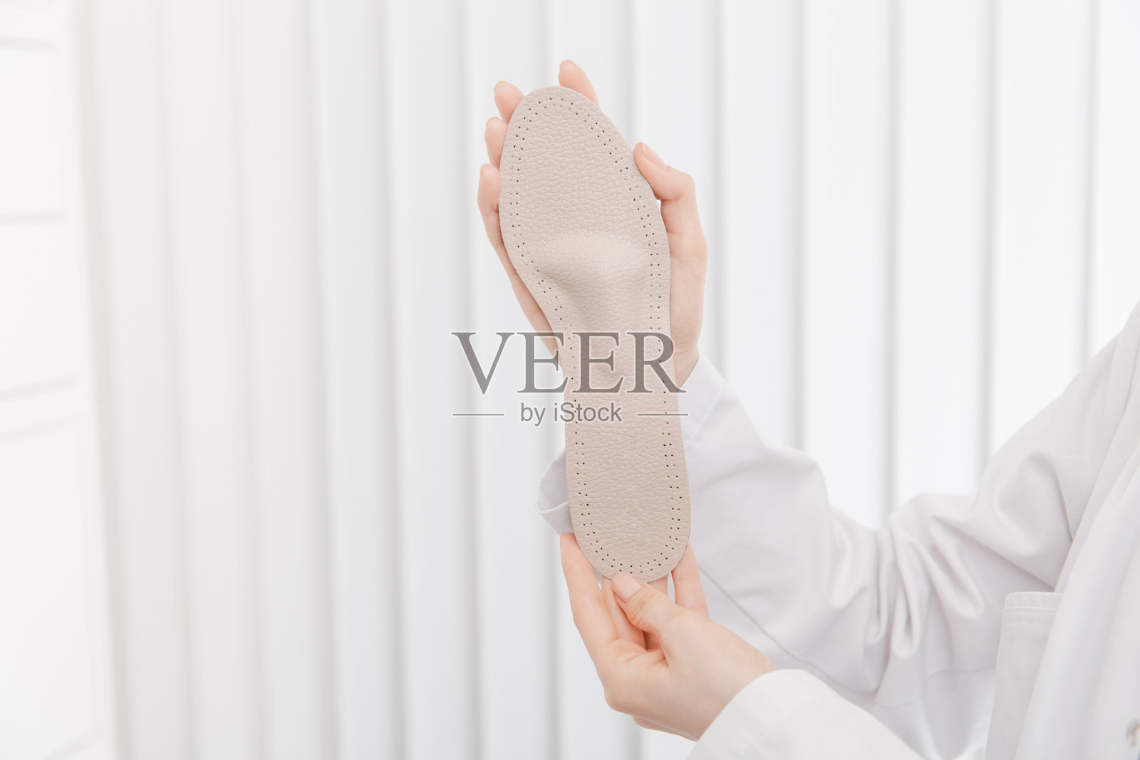 医生手里拿着矫形鞋垫。骨科医生测试医疗设备。矫形鞋垫上的白色。足部护理。扁平足的修正。预防扁平足和足部疾病照片摄影图片