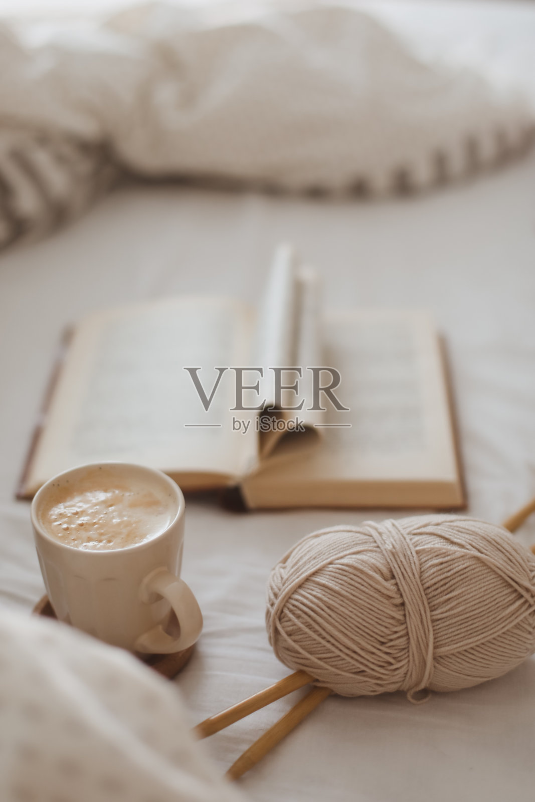 惬意的晨间静物，躺在床上，拿着咖啡杯、针和一本折叠成心形的书照片摄影图片