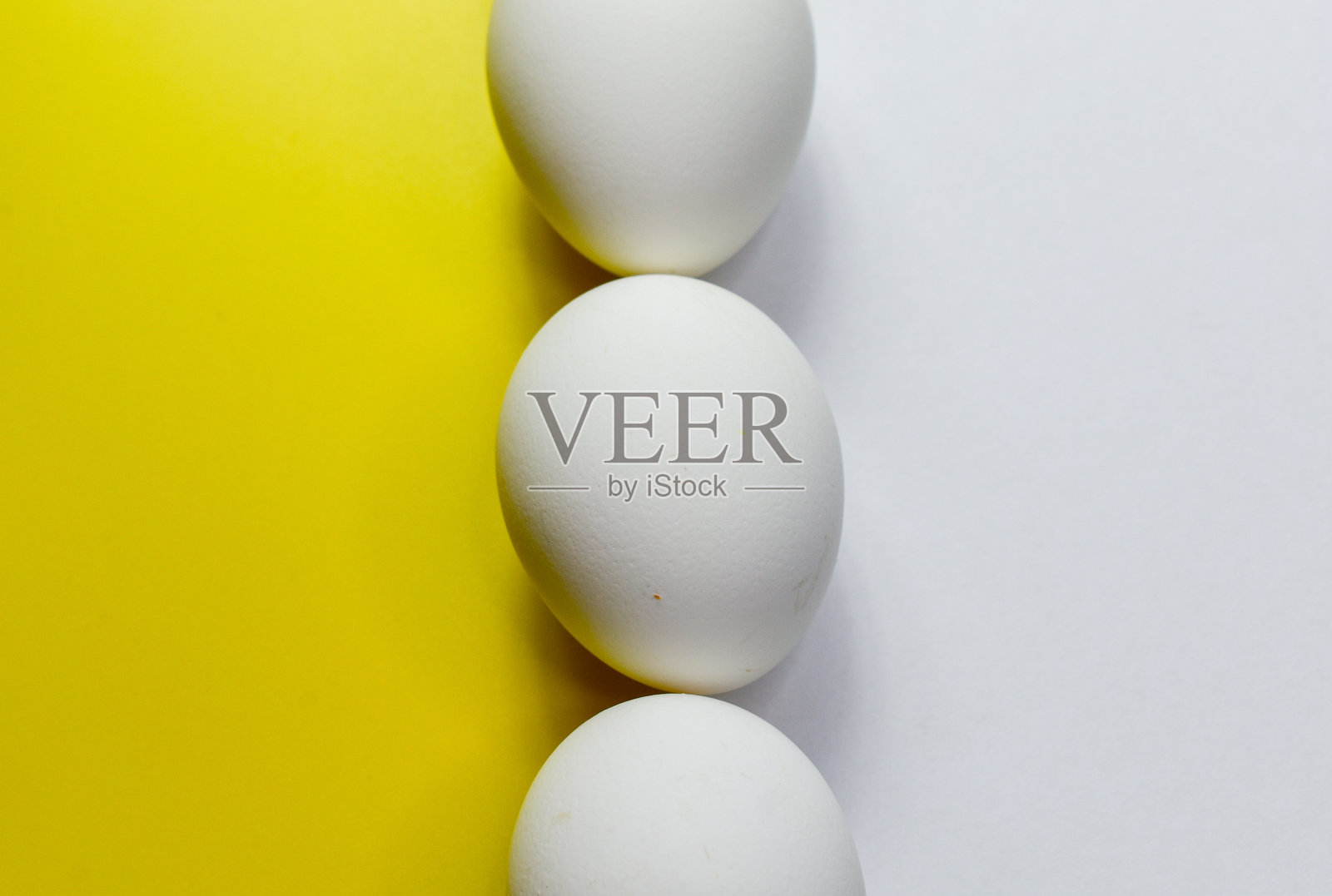 一种由白色的鸡蛋组成，鸡蛋垂直放置在黄色和白色的背景之间照片摄影图片