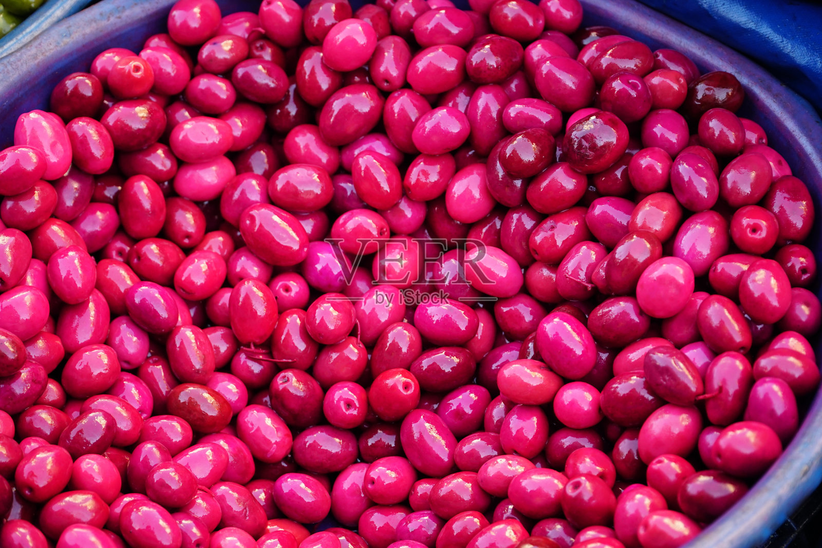 市场上的粉红色橄榄。橄榄上覆着粉红色的甜菜汁色。照片摄影图片