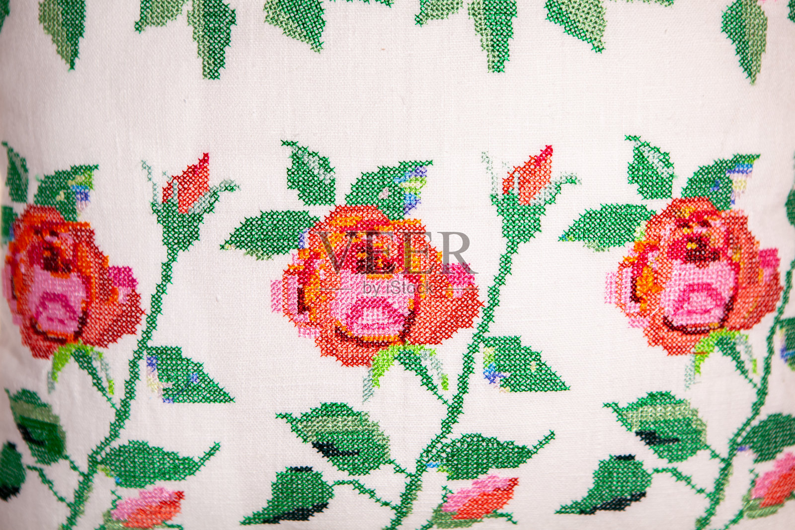 十字绣在白色亚麻枕头上玫瑰的形式，特写。刺绣设计。隔离。照片摄影图片