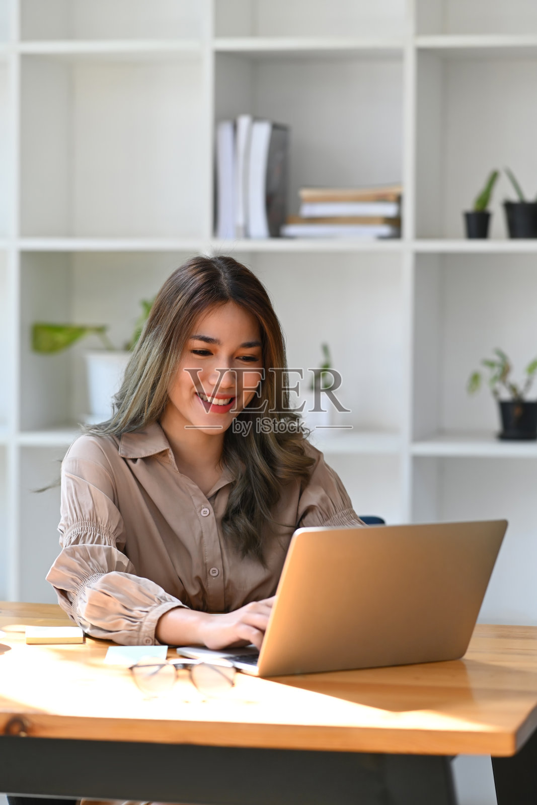 肖像吸引亚洲妇女坐在明亮的现代办公室和工作与笔记本电脑。照片摄影图片