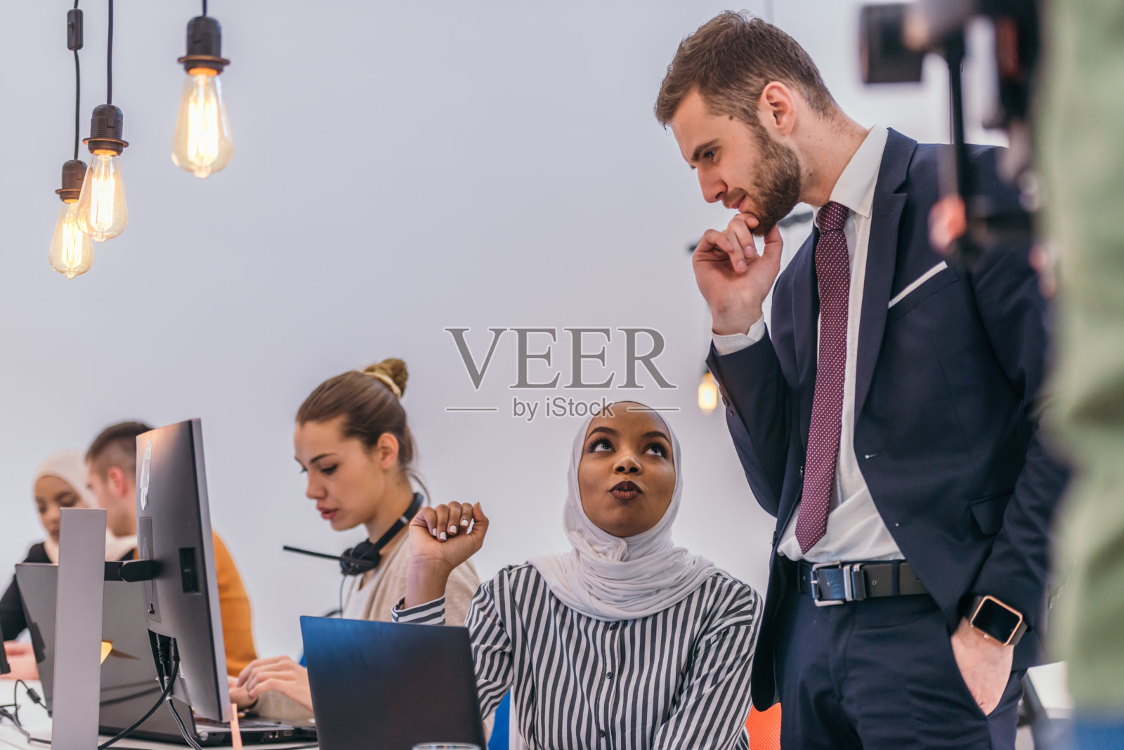 年轻英俊的主管向新员工解释电脑上的在线任务照片摄影图片