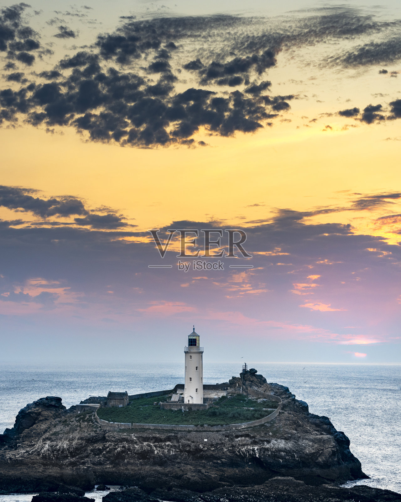 高德雷威岛上的灯塔，太阳在金色的天空下落下，英国，科沃尔。照片摄影图片