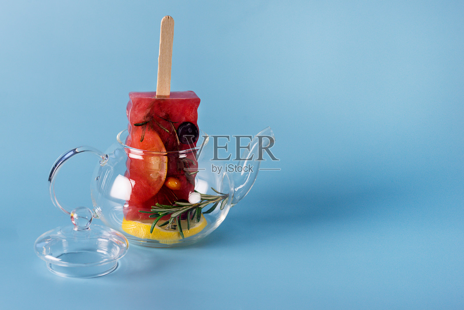 美味健康的夏季甜点自制冷冻浆果和水果冰棒玻璃茶壶冷冻水果茶蓝色背景复制空间水平照片摄影图片