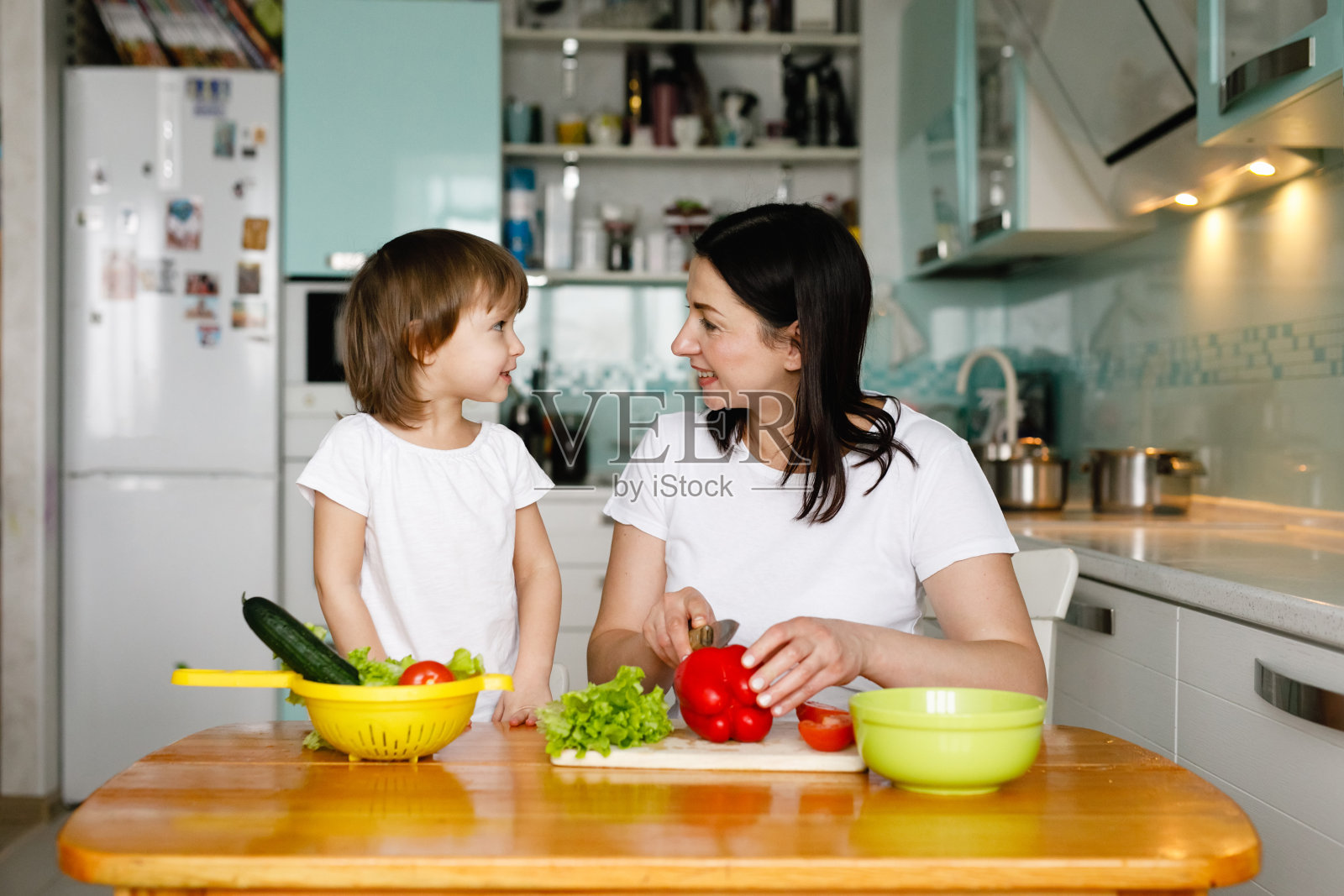 母亲和小女儿在家里的厨房里一起做饭照片摄影图片