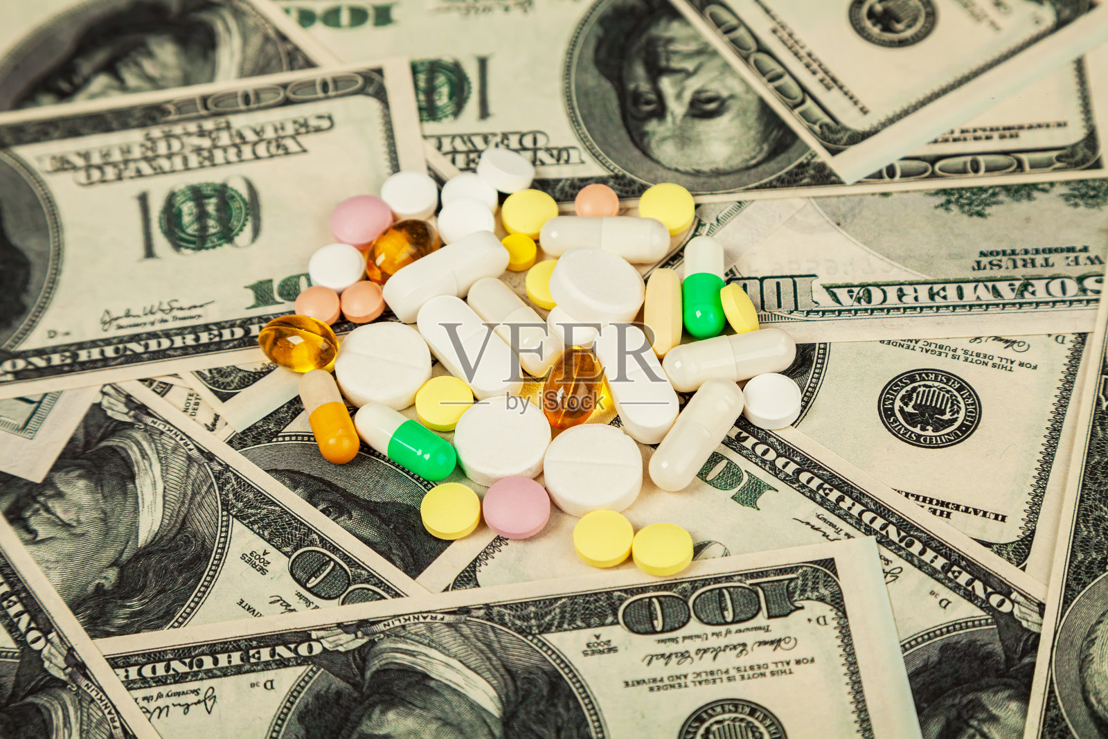新冠病毒药片散落在百元美钞上。一把药丸在美元钞票上的特写。宏观的形象。照片摄影图片