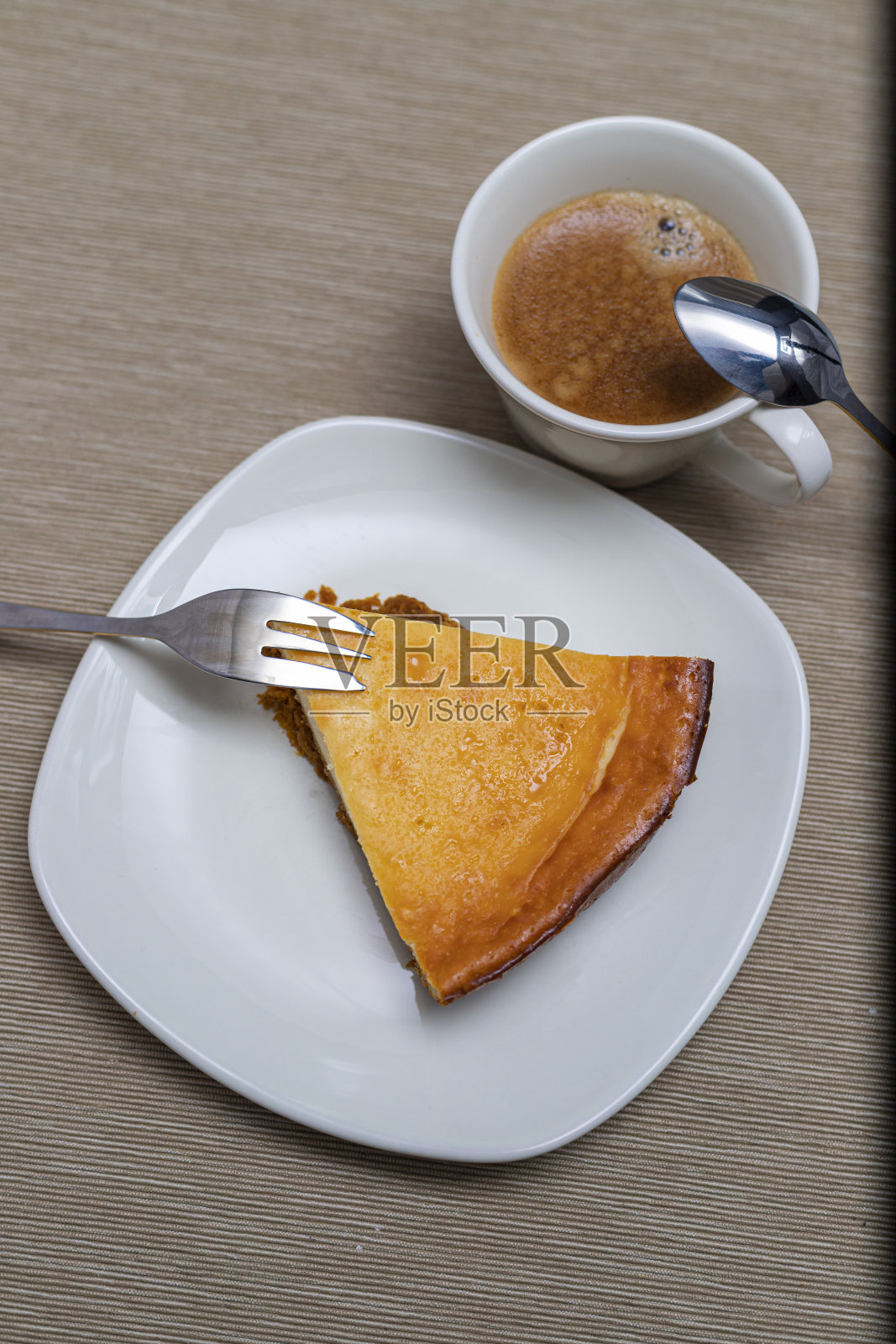 一片芝士蛋糕放在白色的盘子里，配上一杯垂直的咖啡照片摄影图片
