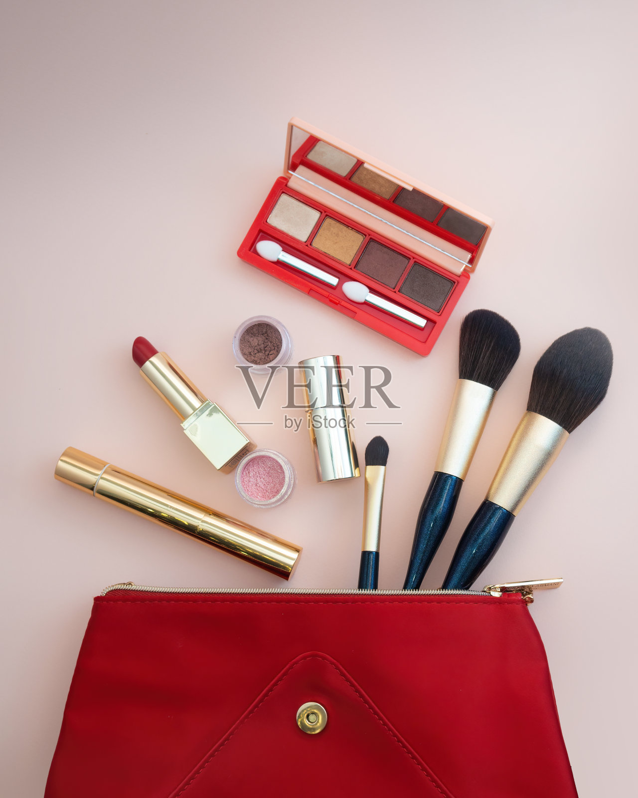 俯视图的化妆品从红色化妆品袋在粉红色的背景中脱颖而出照片摄影图片