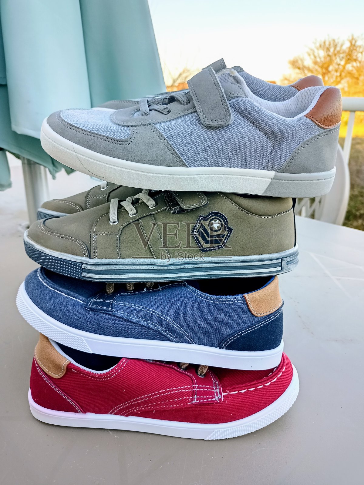 照片上4双灰绿蓝红的童鞋堆放在户外的桌子上照片摄影图片