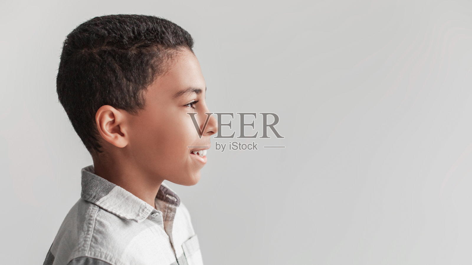 快乐的非洲男孩在灰色背景上摆姿势，全景，侧视图照片摄影图片