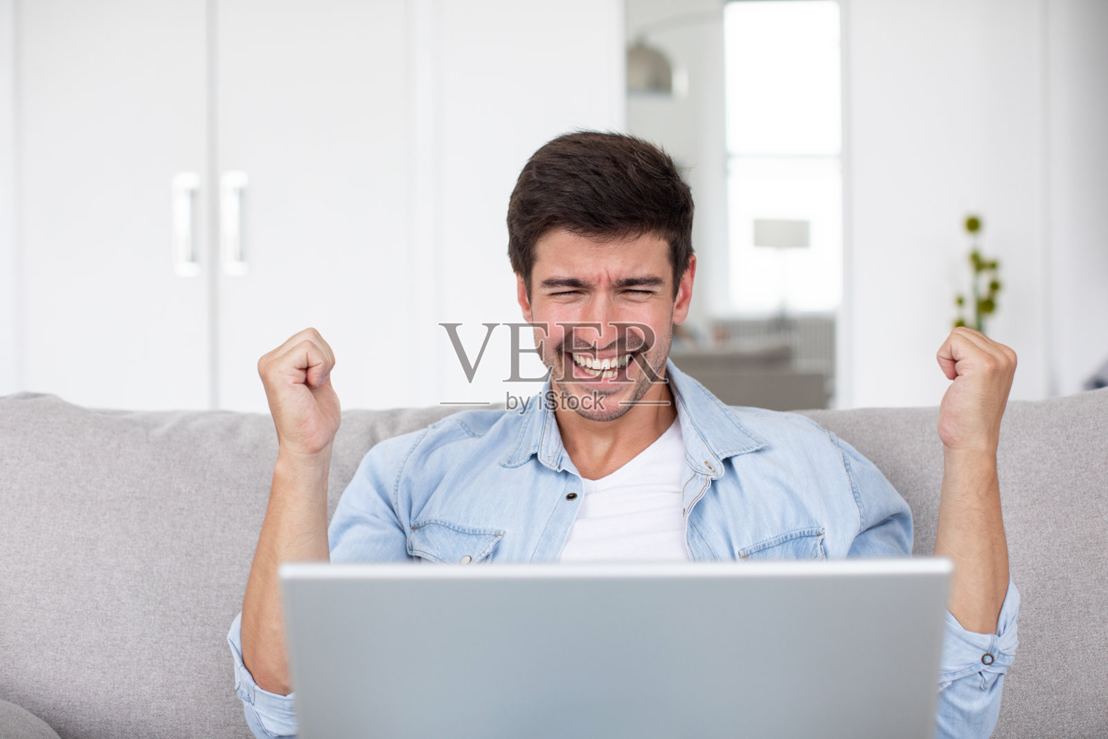 前视图头像年轻快乐的人庆祝胜利，而看着笔记本电脑屏幕。照片摄影图片